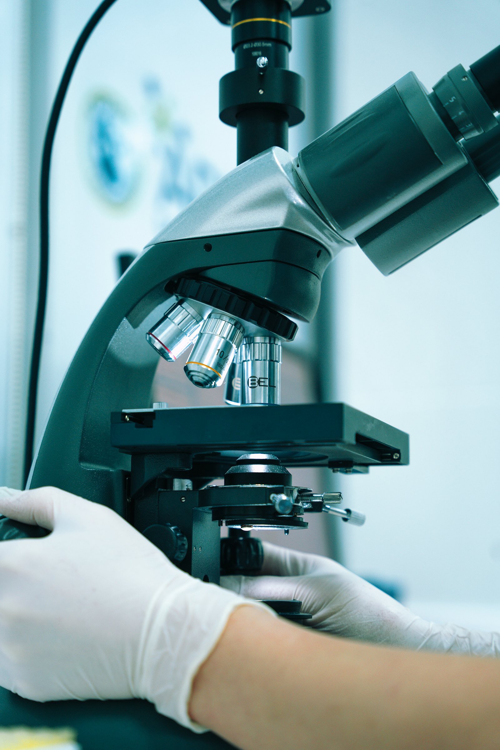 Gloved hand adjusting a microscope