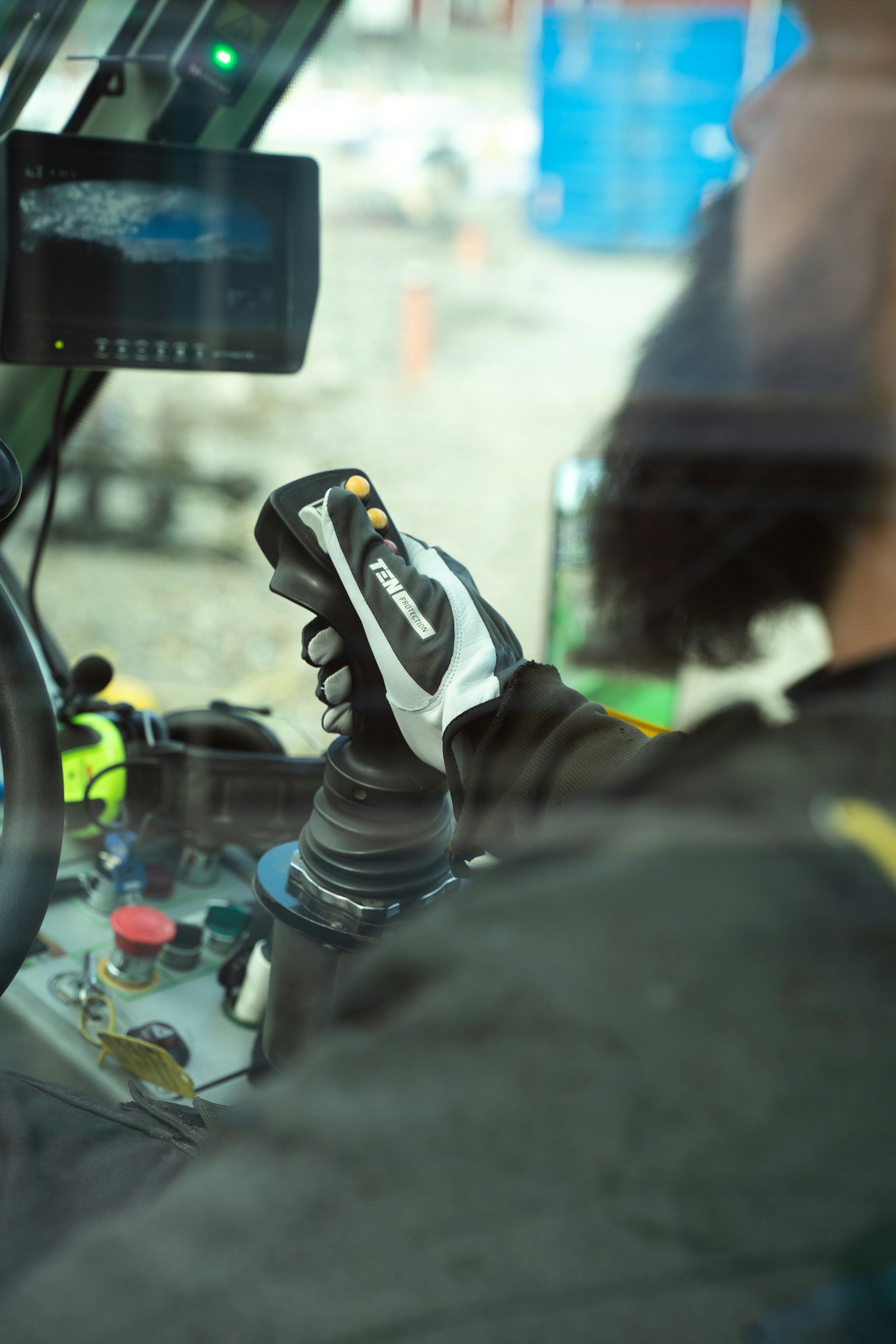 Operator's gloved hand on an excavator joystick
